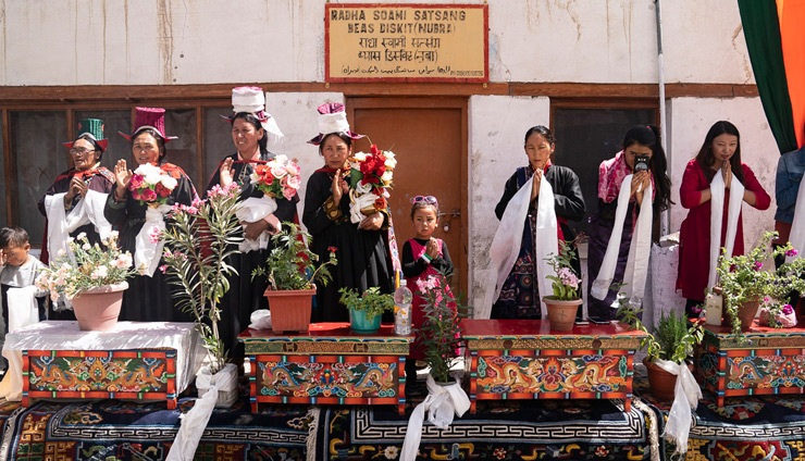 Einheimische stehen an geschnitzten Tischen mit Topfblumen, um Seine Heiligkeit den Dalai Lama zu begrüssen - im Nubra-Tal, Ladakh, J&K, Indien am 12. Juli 2018. Foto: Tenzin Choejor