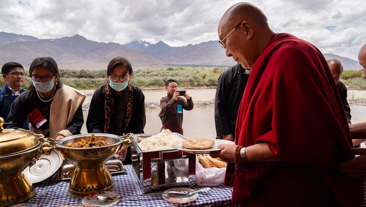 Seine Heiligkeit der Dalai Lama bedient sich am Buffet für das Mittagessen, organisiert vom LAHDC, am Indus in Leh, Ladakh, J&K, Indien am 29. Juli 2018. Foto: Tenzin Choejor