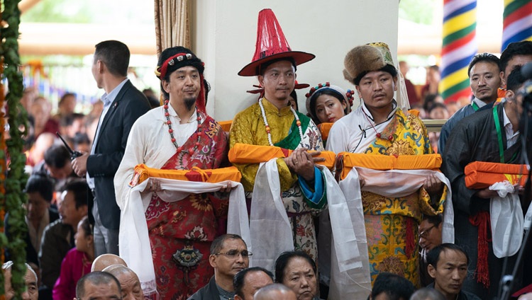 Teilnehmende in den Trachten der drei Provinzen Tibets stehen Schlange um rituelle und symbolische Opfergaben Seiner Heiligkeit dem Dalai Lama darzubringen. In Dharamsala, HP, Indien am 17. Mai 2019. Foto: Tenzin Choejor