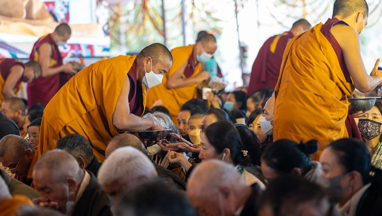 Mönche verteilen rituelle Pillen an die Teilnehmer während der Erlaubnis der 21 Taras am dritten Tag der Unterweisungen Seiner Heiligkeit des Dalai Lama auf dem Kalachakra Teaching Ground in Bodhgaya, Bihar, Indien am 31. Dezember 2022. Foto: Tenzin Choejor