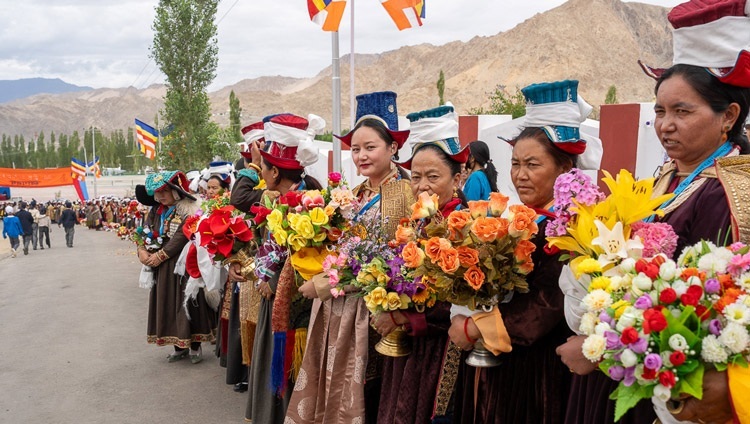 Frauen in traditioneller Kleidung säumen die Straße, während die Autokolonne Seiner Heiligkeit des Dalai Lama sich zur Lamdon Model Senior Secondary School bewegt. In Leh, Ladakh, Indien, 7. August 2023. Foto: Ven Zamling Norbu.