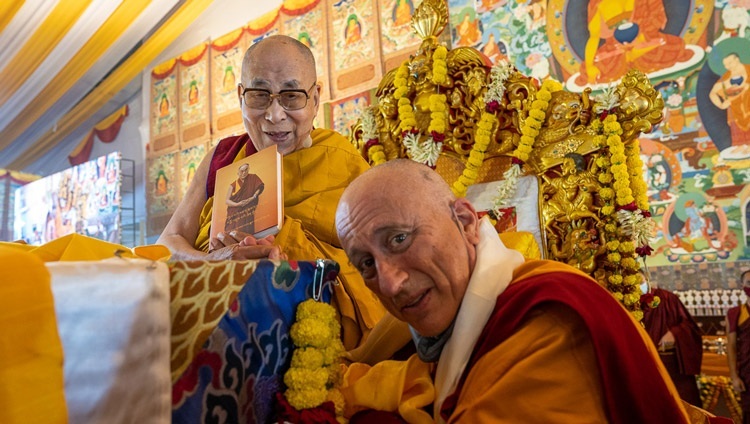 Ratö Khensur, Nicholas Vreeland, überreicht Seiner Heiligkeit dem Dalai Lama das erste Exemplar eines neu erschienenen Buches, das die spirituelle Biographie Seiner Heiligkeit enthält, die vom verstorbenen Ratö Khyongla Rinpoché verfasst wurde, zu Beginn des zweiten Tages der Unterweisungen in Bodhgaya, Bihar, Indien am 30. Dezember 2022. Foto von Tenzin Choejor