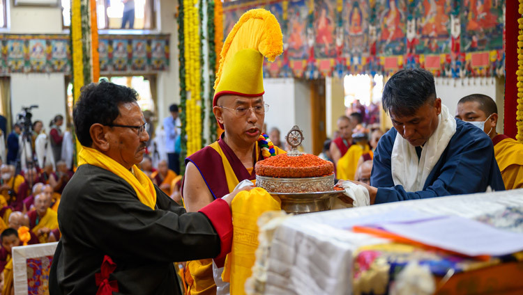 Tenzin, Präsident der Dhotoe Cholkha Welfare Society, Namgyal-Klosterabt Lobsang Samten und Jampa Chhiring Lama, Präsident der Lodrik Welfare Association, überreichen Seine Heiligkeit dem Dalai Lama während des Langlebensgebets im tibetischen Haupttempel ein Mandala. Dharamsala, HP, Indien, 22. April 2026. Foto: Ehrw. Zamling Norbu