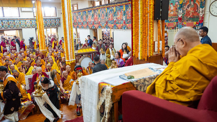 Mitglieder der beiden Gruppen, die das Gebet darbringen, ziehen mit Opfergaben in den Händen an Seiner Heiligkeit dem Dalai Lama vorbei, während des Langlebensgebets im tibetischen Haupttempel. Dharamsala, HP, Indien, 20. Mai 2026. Foto: Tenzin Choejor